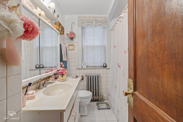 bathroom with radiator, toilet, tile patterned floors, vanity, and tile walls