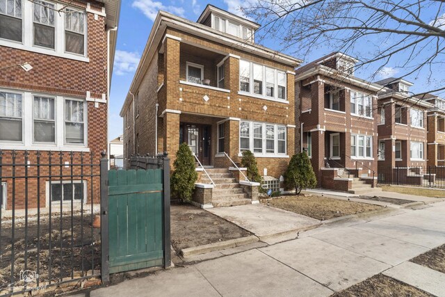 view of front of house featuring brick siding, fence, and a gate