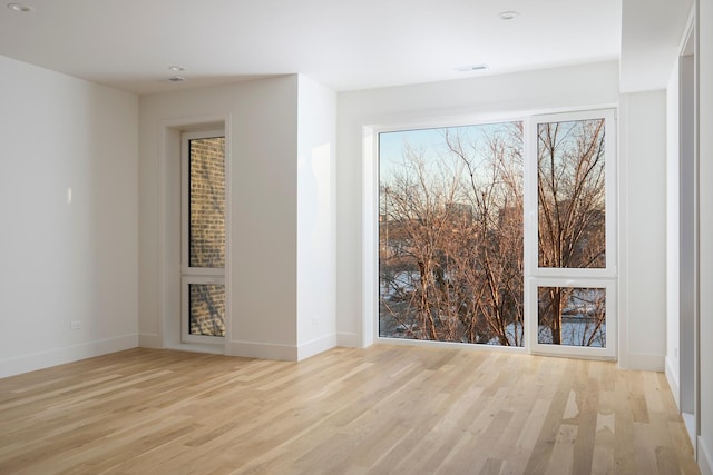 spare room with light wood-style floors, baseboards, and visible vents