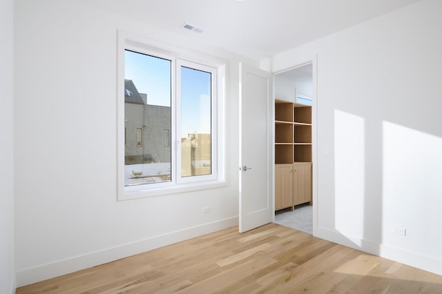 unfurnished bedroom featuring baseboards, visible vents, and wood finished floors