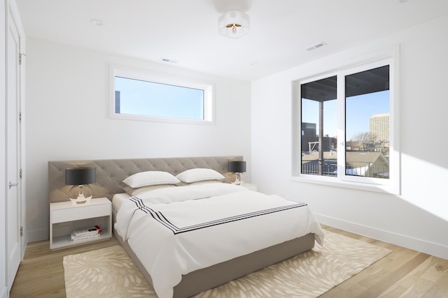 bedroom featuring baseboards, light wood-style flooring, and visible vents