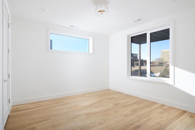 spare room featuring baseboards, light wood finished floors, and visible vents