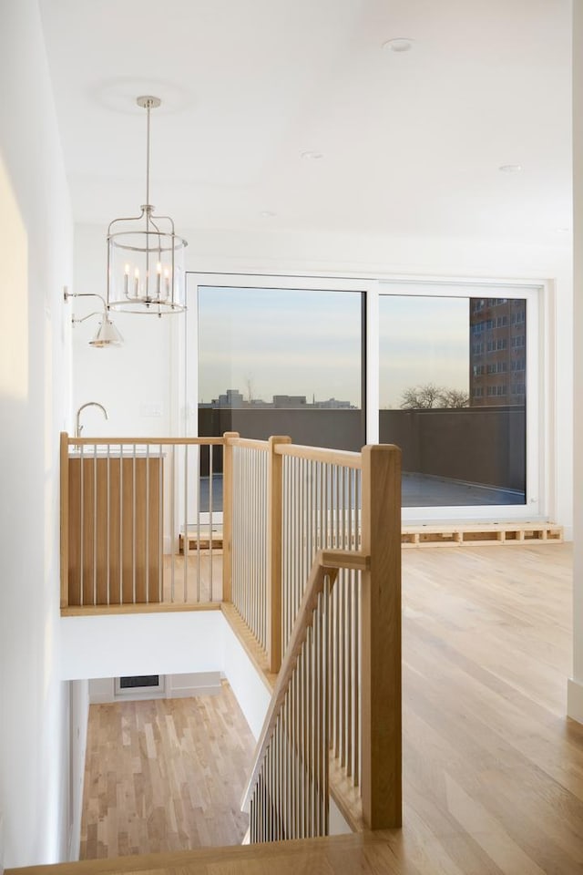 interior space with wood finished floors, a notable chandelier, and an upstairs landing