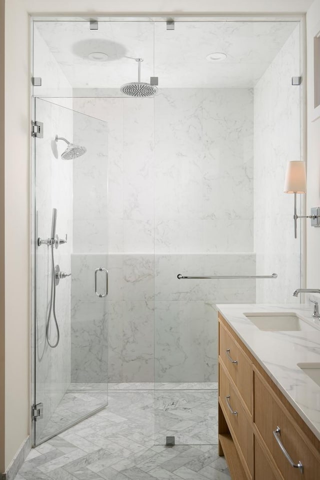 full bathroom with a sink, a marble finish shower, double vanity, and marble finish floor