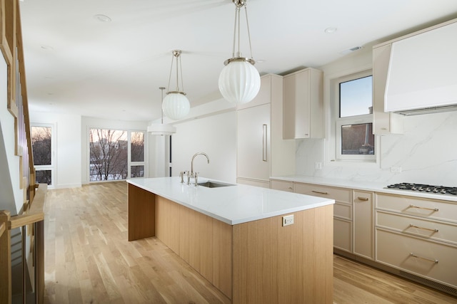kitchen featuring gas cooktop, a healthy amount of sunlight, a sink, and wall chimney exhaust hood