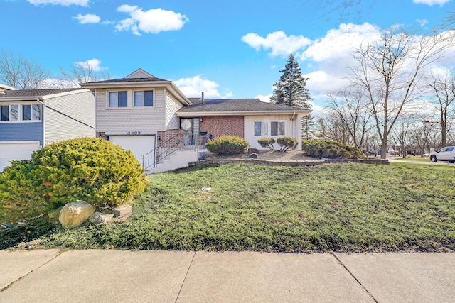 tri-level home featuring brick siding, an attached garage, and a front lawn