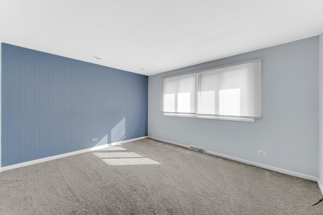 carpeted spare room featuring visible vents and baseboards