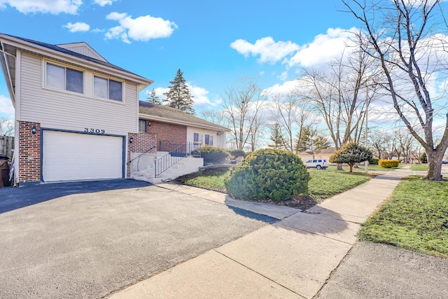 view of property exterior with driveway, a garage, and brick siding