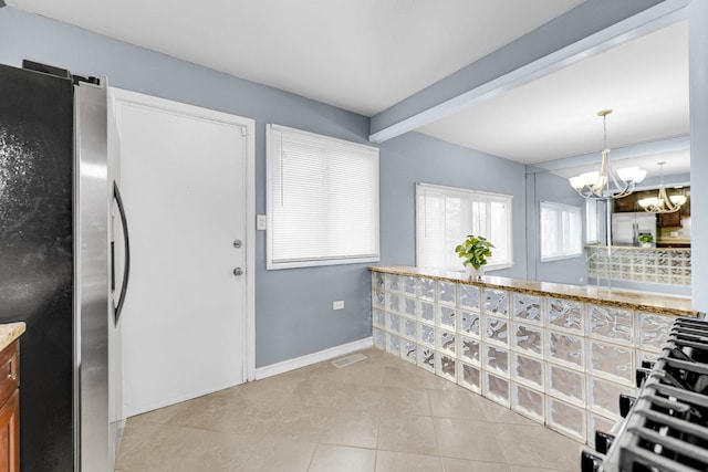 kitchen featuring an inviting chandelier, freestanding refrigerator, light tile patterned flooring, beamed ceiling, and baseboards