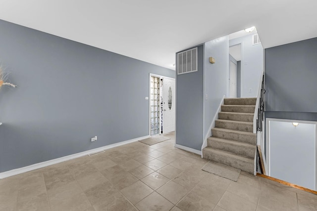 staircase featuring baseboards, visible vents, and tile patterned flooring