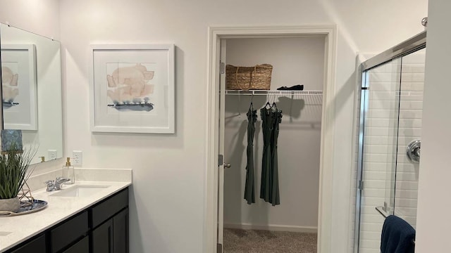 full bathroom with double vanity, a tile shower, a walk in closet, and a sink