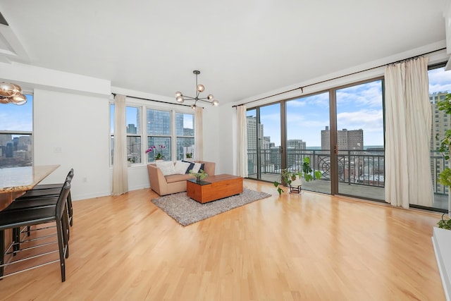 living room with light wood-type flooring, an inviting chandelier, baseboards, and a city view