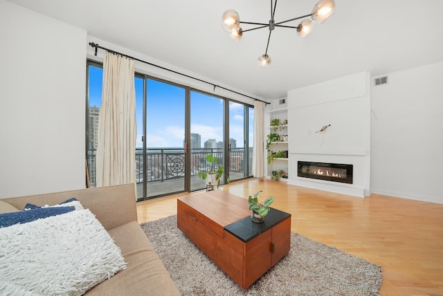 living room with baseboards, visible vents, a glass covered fireplace, a view of city, and light wood-type flooring