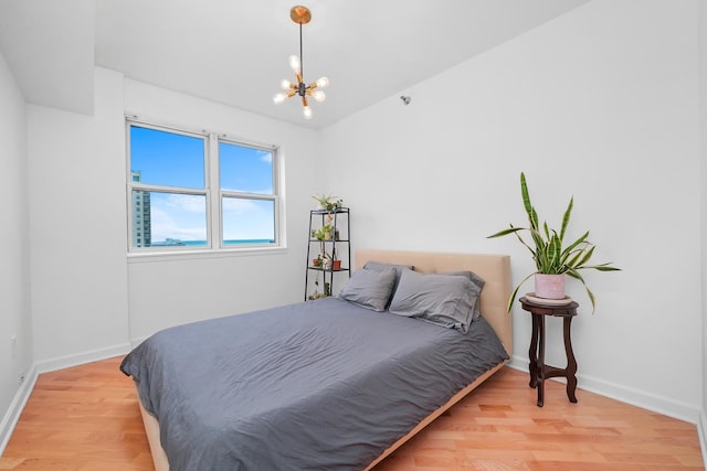 bedroom with light wood-style floors, lofted ceiling, a chandelier, and baseboards