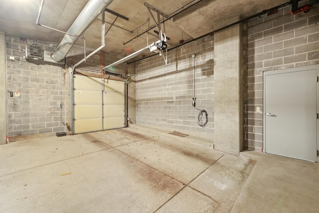 parking garage featuring concrete block wall and a garage door opener