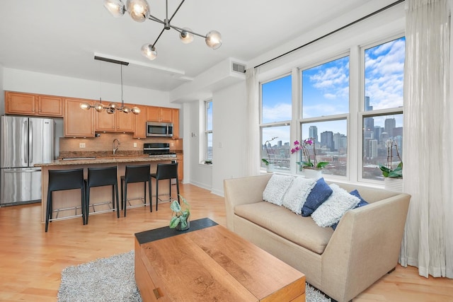 living room with light wood-style floors, visible vents, a notable chandelier, and a city view