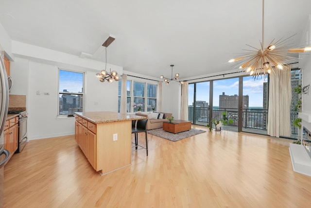 kitchen featuring a breakfast bar area, stainless steel gas range, light wood-style flooring, light brown cabinets, and a chandelier