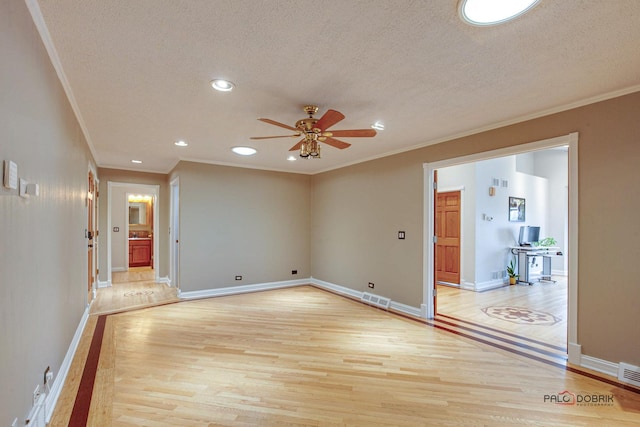 spare room featuring baseboards, light wood-style flooring, visible vents, and a textured ceiling