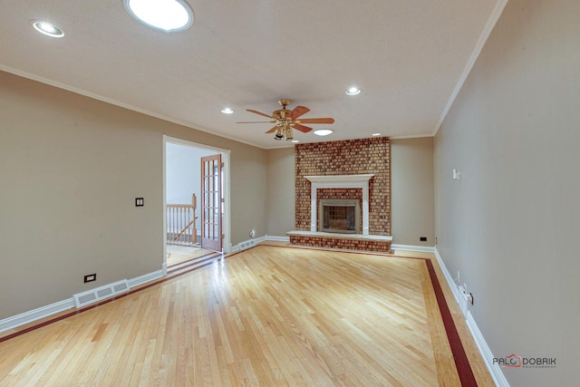 unfurnished living room featuring hardwood / wood-style flooring, baseboards, a brick fireplace, and visible vents