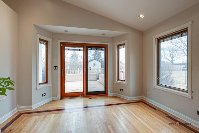 entryway featuring light wood-type flooring, lofted ceiling, a healthy amount of sunlight, and baseboards