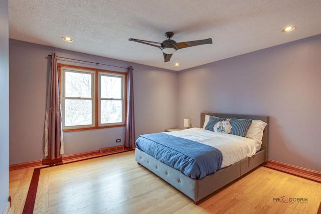 bedroom featuring baseboards, visible vents, a textured ceiling, light wood-type flooring, and recessed lighting