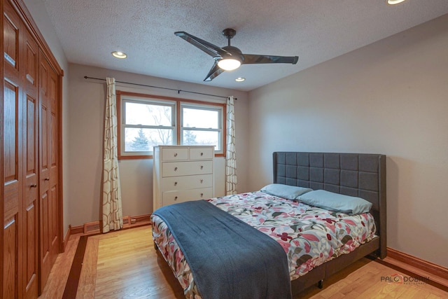 bedroom featuring light wood finished floors, baseboards, ceiling fan, a textured ceiling, and a closet