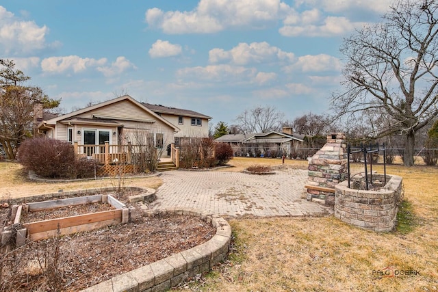 view of yard featuring a patio, a fireplace, fence, a garden, and a wooden deck