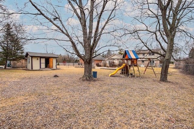 view of yard featuring an outbuilding, a playground, and fence