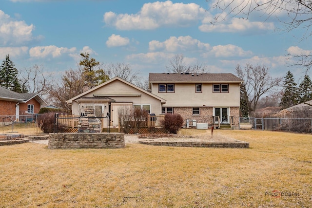 rear view of house with brick siding, a yard, a gate, a deck, and a fenced backyard