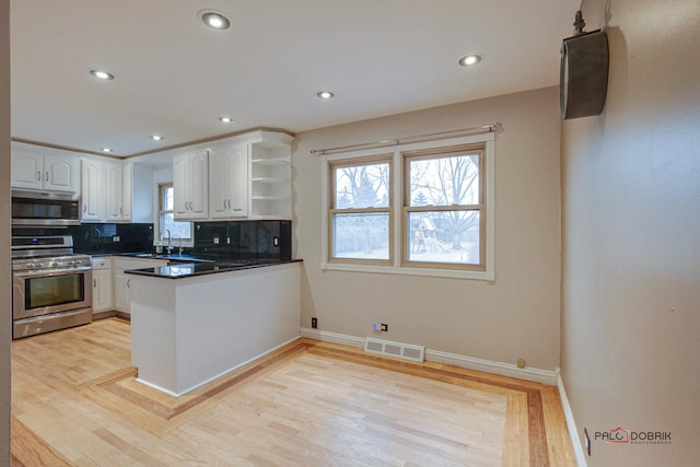 kitchen featuring a peninsula, visible vents, white cabinetry, appliances with stainless steel finishes, and open shelves