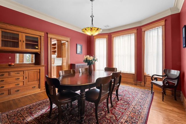 dining space featuring radiator, light wood-type flooring, visible vents, and crown molding