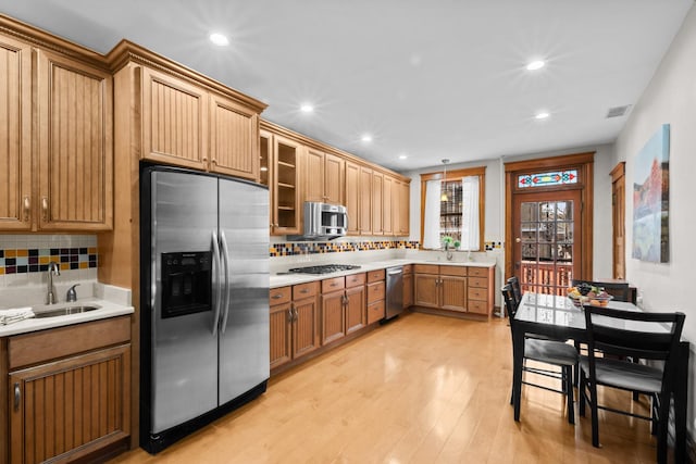 kitchen with stainless steel appliances, light countertops, a sink, and light wood-style flooring