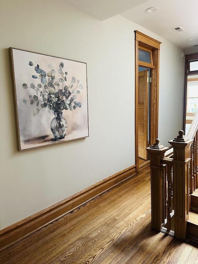 corridor featuring baseboards, visible vents, and wood finished floors