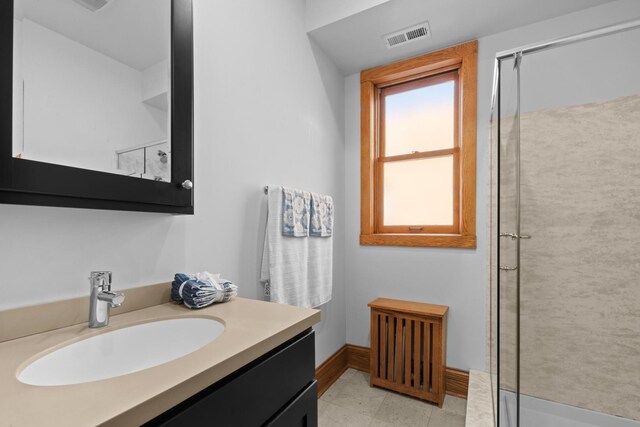 bathroom featuring baseboards, vanity, visible vents, and a shower with shower door