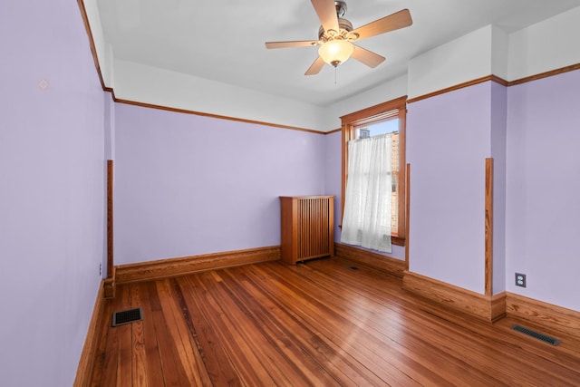 empty room with baseboards, visible vents, and hardwood / wood-style floors