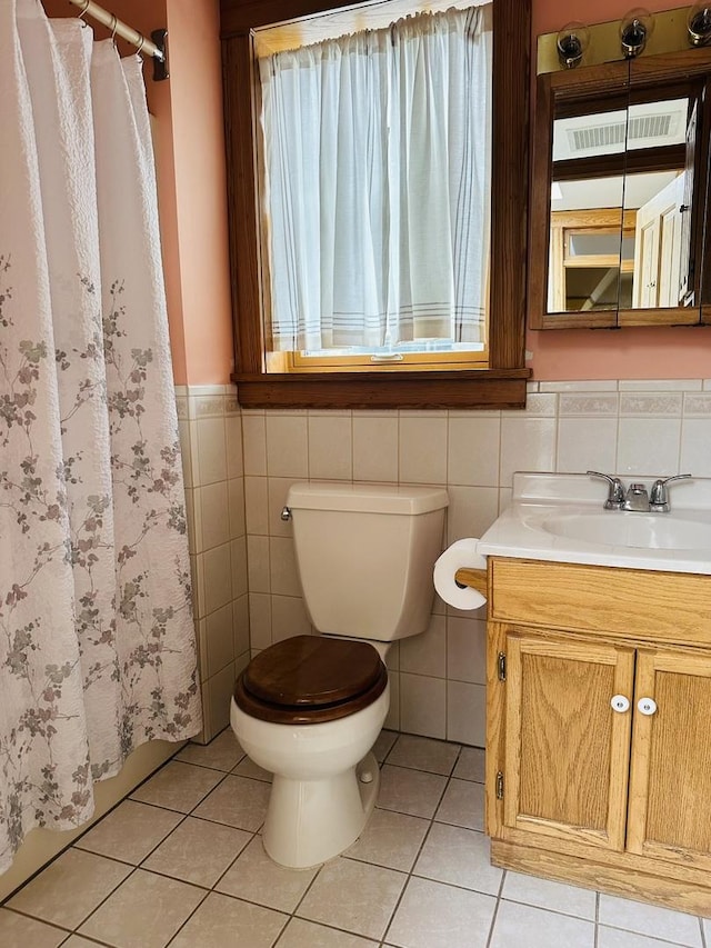 bathroom featuring toilet, vanity, tile walls, and tile patterned floors