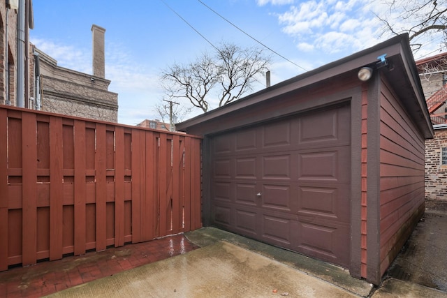 detached garage featuring driveway and fence