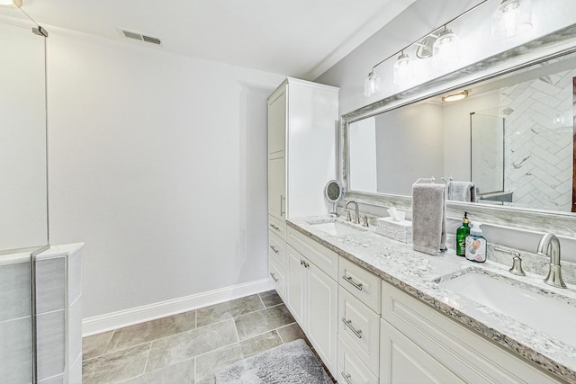 bathroom with double vanity, baseboards, visible vents, and a sink