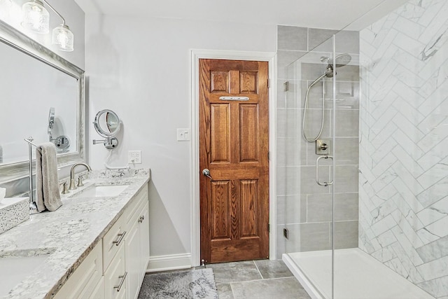 bathroom with a sink, baseboards, a stall shower, and double vanity