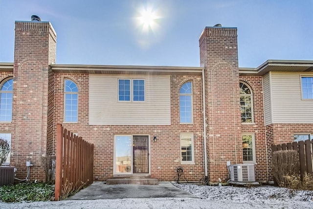 back of house with cooling unit, fence, brick siding, and a chimney