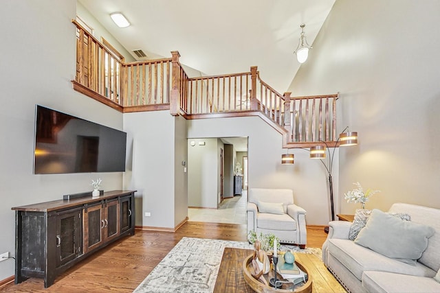 living room featuring stairway, baseboards, a high ceiling, and wood finished floors