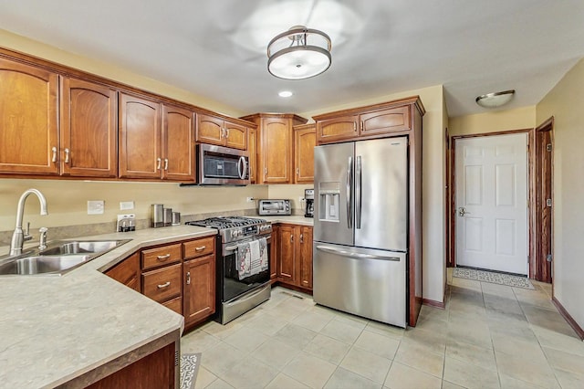 kitchen featuring light countertops, light tile patterned floors, appliances with stainless steel finishes, brown cabinetry, and a sink