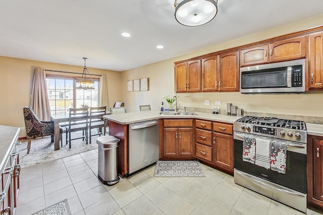 kitchen featuring pendant lighting, a sink, stainless steel appliances, a peninsula, and light countertops