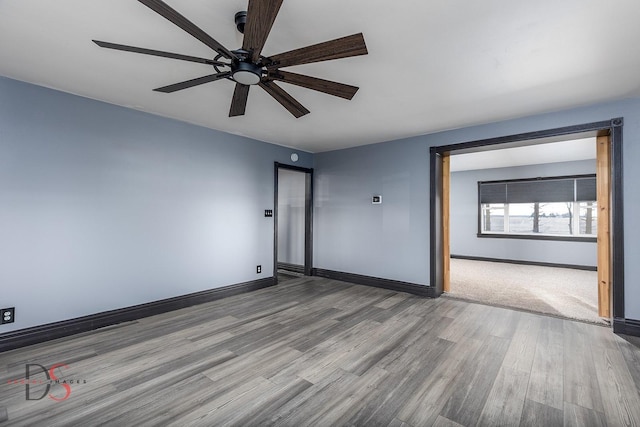 empty room featuring ceiling fan, baseboards, and wood finished floors