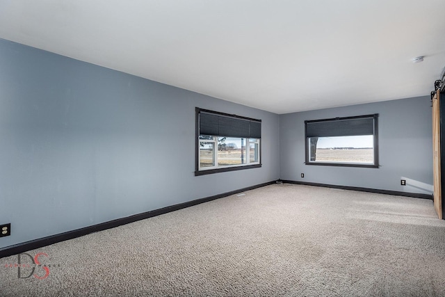 carpeted empty room featuring baseboards