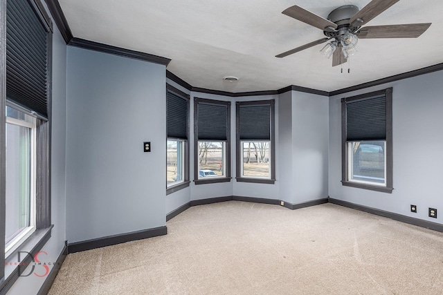 unfurnished room with a ceiling fan, baseboards, crown molding, and carpet flooring