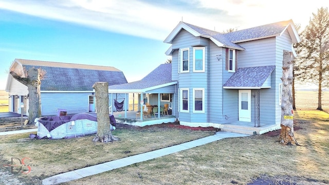 view of front facade with a front lawn, roof with shingles, and a sunroom