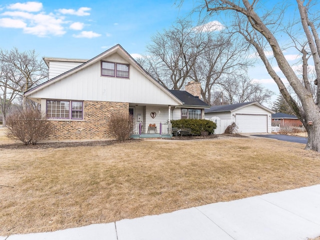 view of front of property with covered porch, a chimney, a front lawn, and brick siding