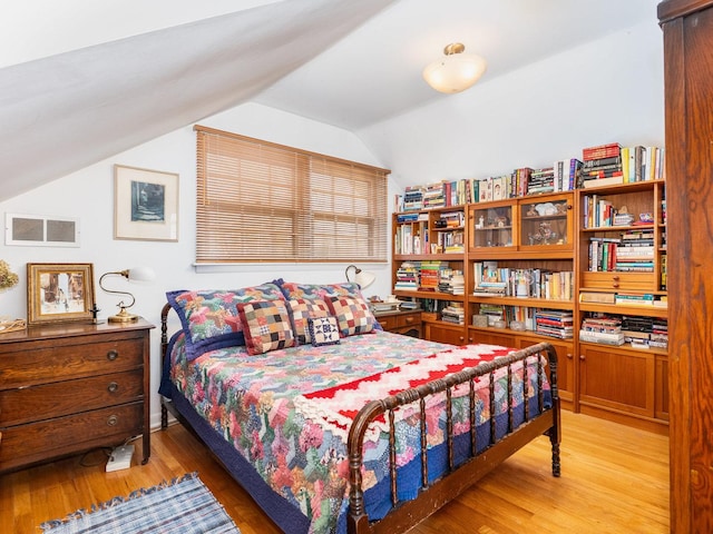 bedroom with lofted ceiling, visible vents, and light wood-style floors