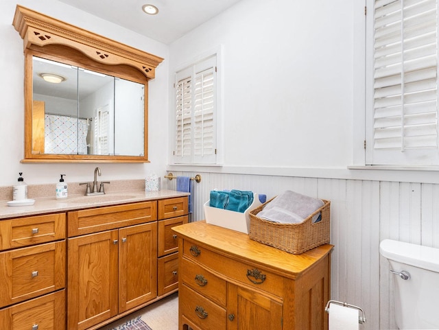 full bathroom featuring wainscoting, vanity, and toilet